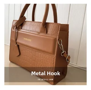 Détail du sac en cuir crocodile marron avec crochets argentés et logo doré