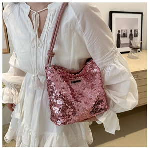Détail du sac à bandoulière à paillettes roses avec étiquette FASHION porté par un mannequin