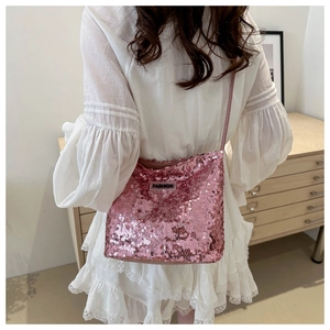 Détail du sac bandoulière à paillettes roses avec étiquette FASHION porté par un mannequin