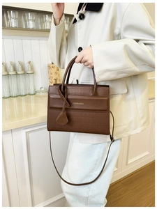 Gros plan sur un sac à main rétro marron foncé avec texture crocodile et doubles anses