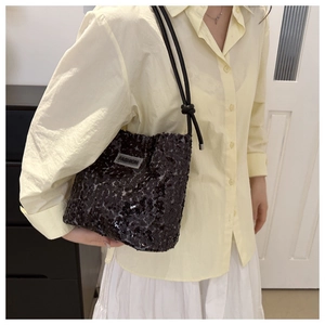 Détail d'un sac à bandoulière noir à paillettes avec étiquette Fashion et nœud
