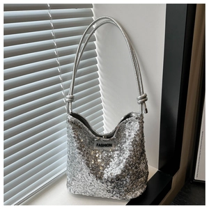 Détail d'un sac à main argenté à paillettes avec étiquette de mode sur un rebord de fenêtre