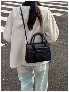 Détail du sac à main noir à motif crocodile avec texte doré Fashion & Bags dans la rue