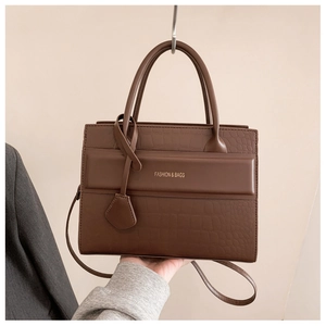 Détail d'un sac à main marron foncé avec texture crocodile et lettrage doré chic