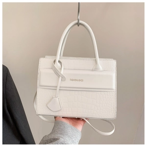 Détail du sac à main blanc à texture croco avec inscription dorée élégante