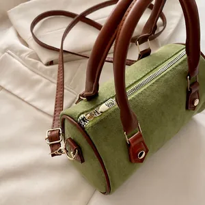 Détail du sac polochon en daim vert avec fermeture éclair dorée et poignée en cuir brun