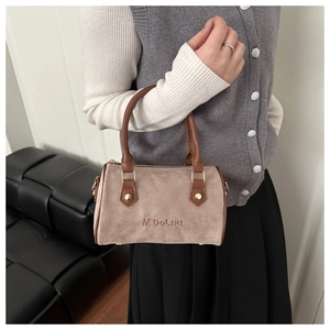 Détail d'un sac Boston en daim fauve avec gaufrage de marque et poignée en cuir