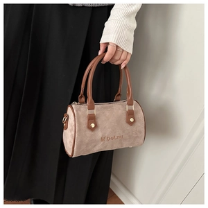 Détail du sac Boston montrant la texture suédée, les anses en PU brun et logo