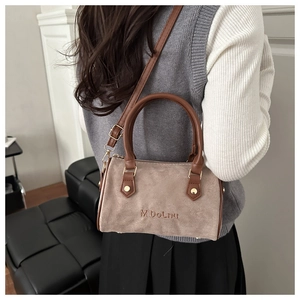 Détail d'un sac Boston en daim mocha avec poignées en cuir et finitions dorées