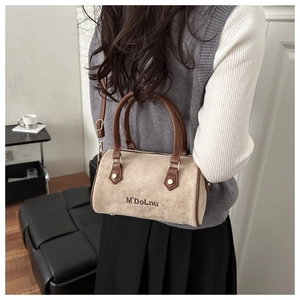 Détail d'un sac Boston en daim beige avec poignées en cuir brun et broderie