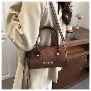 Gros plan sur le sac Boston en daim marron avec broderie et poignée en cuir souple