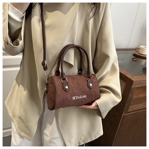 Gros plan du sac Boston en daim marron avec poignées en cuir et bandoulière réglable