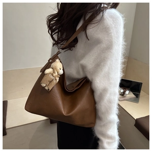 Vista laterale borsa tote marrone con ciondolo a orsetto per uno stile ufficio casual