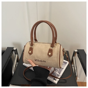 Détail d'un sac Boston en daim beige avec poignées en cuir marron et logo brodé