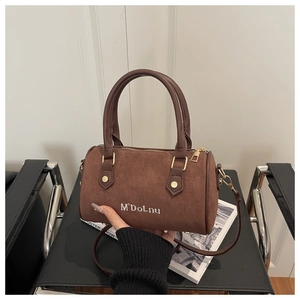 Vue détaillée du mini sac Boston en daim marron avec logo brodé blanc et finitions dorées