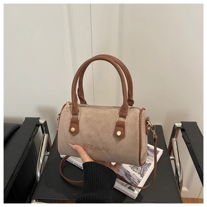 Détail du sac Boston en daim beige avec anses marron et logo embossé élégant
