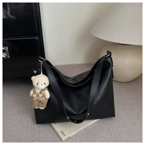 Dettaglio della texture della borsa tote nera in similpelle con ciondolo a orsetto