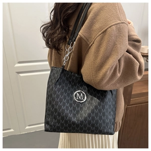Detail of monogram M print tote bag with silver chain strap and metal logo plaque