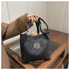 Detail of grey tote bag featuring M-letter print and silver metallic logo decoration
