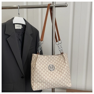 Detail of beige monogram tote bag with brown leather strap and silver chain links