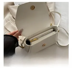 Detail showing smooth gold metal zipper and magnetic closure of the white crossbody bag