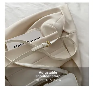 Detail of adjustable shoulder strap with gold metal buckle on white leather bag