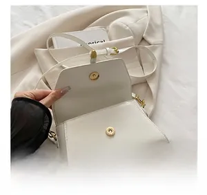 Detail of white vintage crossbody bag with gold magnetic buckle and adjustable strap