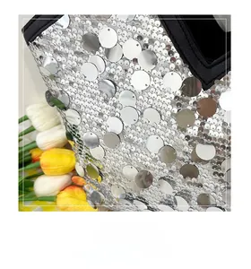 Macro view of silver sequins and black fabric trim on a stylish evening tote bag