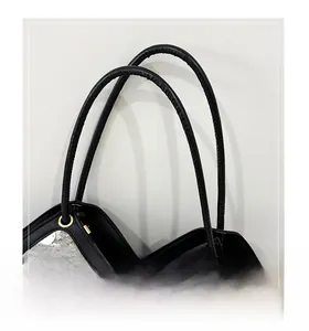 Detailed macro view of black leather shoulder bag featuring silver sequins and gold eyelets