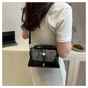Detailed view of women's black leather crossbody bag with silver glitter flap and gold clasp