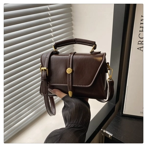 Detailed view of deep brown vintage leather bag with retro golden circular buckle and strap