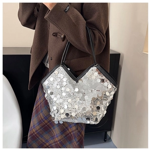Detail of silver sequin handbag with black straps paired with a brown wool coat
