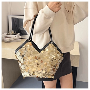 Detail of gold sequin tote bag with V-shaped opening and black leather shoulder straps
