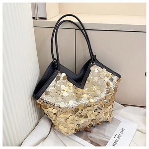 Detail of shimmering gold sequins on a tote bag with black leather handles and V-shaped opening