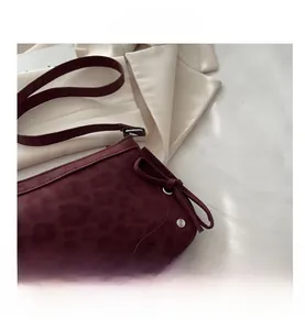 Detail of wine red suede bag featuring leopard texture with bow and silver rivets