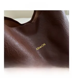 Vue détaillée du sac en cuir marron texturé avec logo doré et finitions soignées