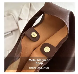 Gros plan d'un fermoir magnétique en métal sur un sac cabas vintage en cuir marron