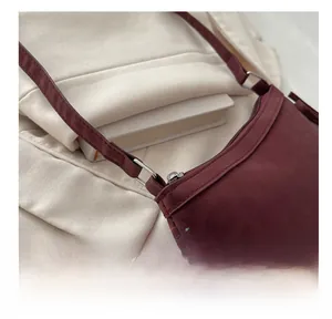 Detail of the metal ring strap attachment on a burgundy matte leather crossbody bag