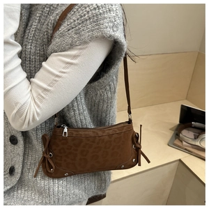 Detail of leopard print suede shoulder bag featuring decorative side bows and silver studs
