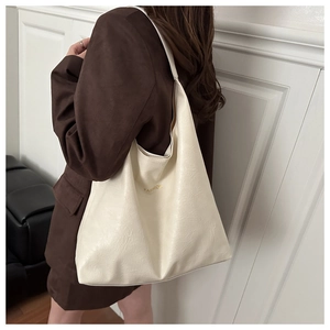 Modèle portant un grand sac cabas en simili cuir crème avec logo doré élégant