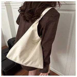 Détail d'un sac cabas en similicuir blanc crème avec lettrage doré sur l'épaule
