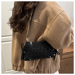 Detail shot of leopard print shoulder bag with silver studs on soft black suede fabric