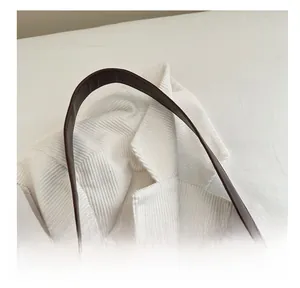 Détail rapproché de l'anse en similicuir marron foncé et de la texture du tissu
