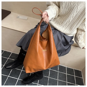 Détail du grand sac cabas marron en similicuir avec texte FASHION doré sur un banc
