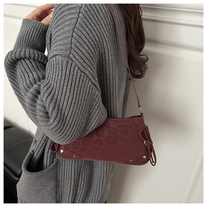Detail of burgundy leopard print shoulder bag featuring decorative bow and metal studs