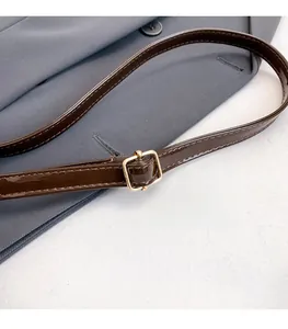 Macro shot of adjustable dark brown glossy shoulder strap with gold metal square buckle