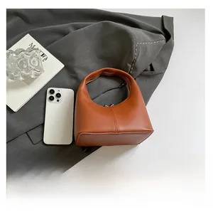 Detailed flat lay of minimalist caramel orange handbag on a grey suit jacket background