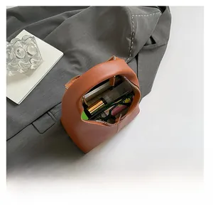 Internal capacity of brown leather handbag showing phone and cosmetics on grey blazer