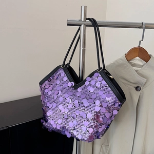Sparkly purple sequin tote bag with black leather shoulder straps on a display rack