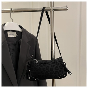 Detail view of leopard print underarm bag with black ribbon bow and silver metal rivets